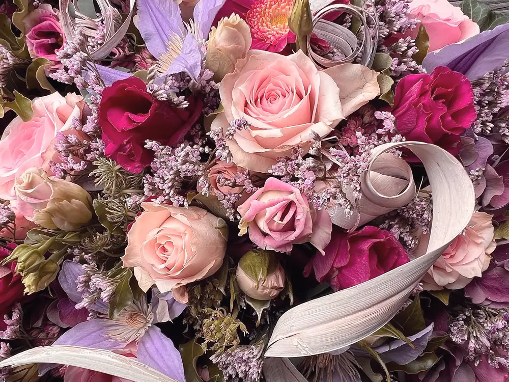 Nahaufnahme eines Gestecks mit Rosen und Schleife